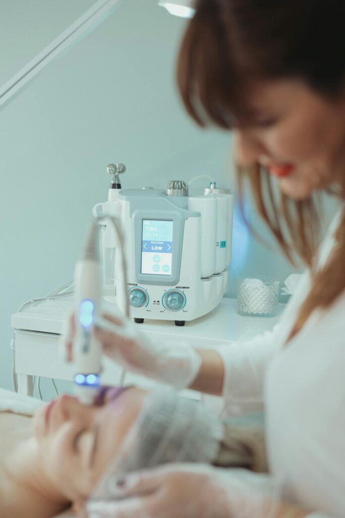 Hydrafacial Gesicht Behandlung – Kosmetikerin reinigt die Haut mit einem speziellen Gerät.