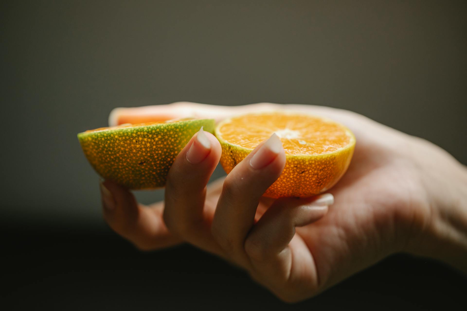Hand hält frische Orange – Symbol für Vitamin-C-Infusion und natürliche Hautpflege